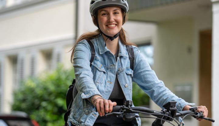 FALTER Faltrad in zwei Zuständen: links vollständig entfaltet, rechts zusammengefaltet und von einer Person getragen – beide vor einer Backsteinwand.